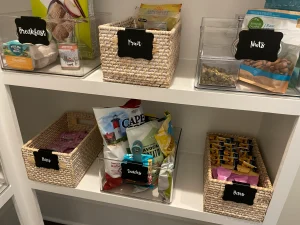 Organized pantry shelves with woven baskets and clear bins featuring simple chalkboard labels for ADHD-friendly food storage.